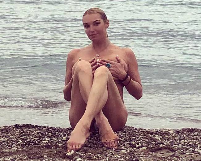Девушка надевает купальник на пляже оголив грудь фото